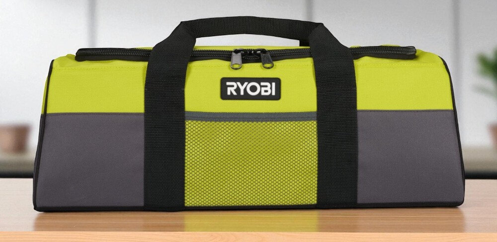 Torba narzędziowa RYOBI RTB02 pomieszczenie drewniany blat torba widoczna od przodu stoi na blacie rozmazane tło organizacja pracy praktyczny gadżet mobilność solidność
