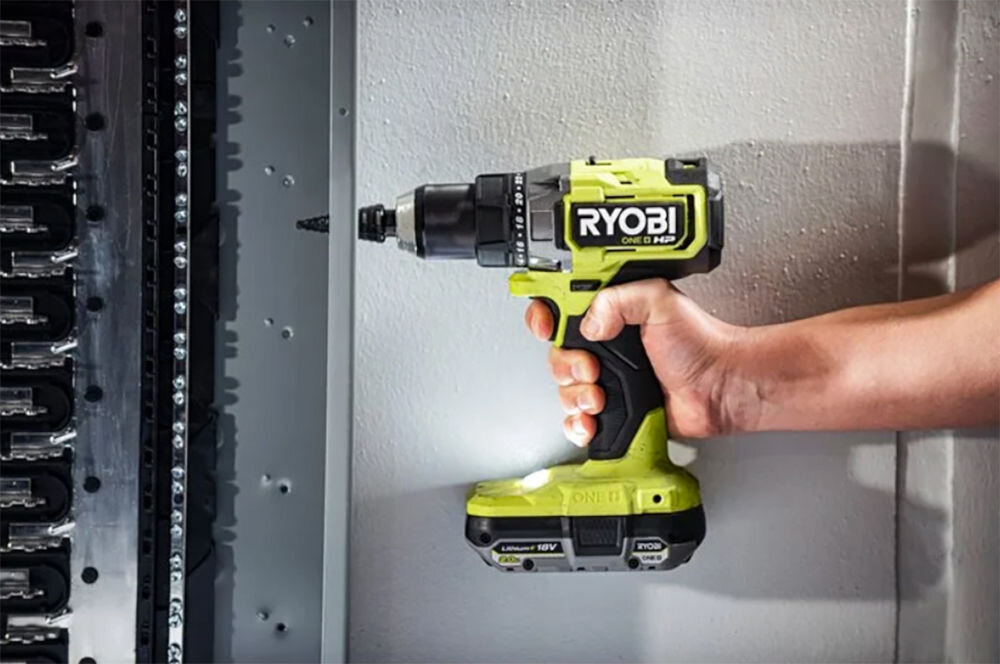 Akumulator RYOBI RB1820C 2Ah 18V, pojemność, 2Ah, czas, ogród, Wkrętarka wierci w ścianie wraz z podpiętym do niej akumulatorem