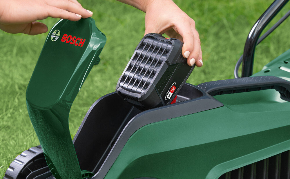 Kosiarka akumulatorowa BOSCH EasyMower 18V-32-200 06008B9D00 osoba umieszcza akumulator w kosiarce zasilana akumulatorem z uniwersalnej serii Bosch Power For All 18 V niezależność od źródła zasilania praca w dowolnym miejscu w zestawie jeden akumulator 18 V o pojemności 4,0 Ah i ładowarka