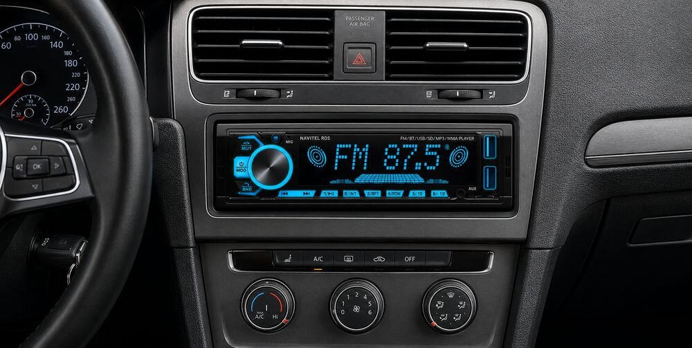 Obraz przedstawia radio samochodowe z wyświetlaczem pokazującym \'FM 87.5\' oraz rękę wskazującą na jasny punkt na tle sieci połączeń. Na radiu widoczny jest napis \'NAVITEL RD5\'.