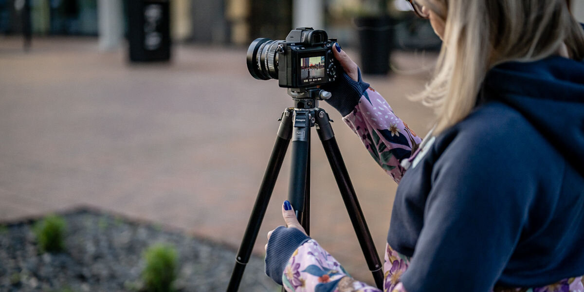 Statyw FOTOPRO Fly-1 Szary, konstrukcja, centralny, rozmiar, redukcja, osoba obsługuje statyw z zamontowanym aparatem na nim