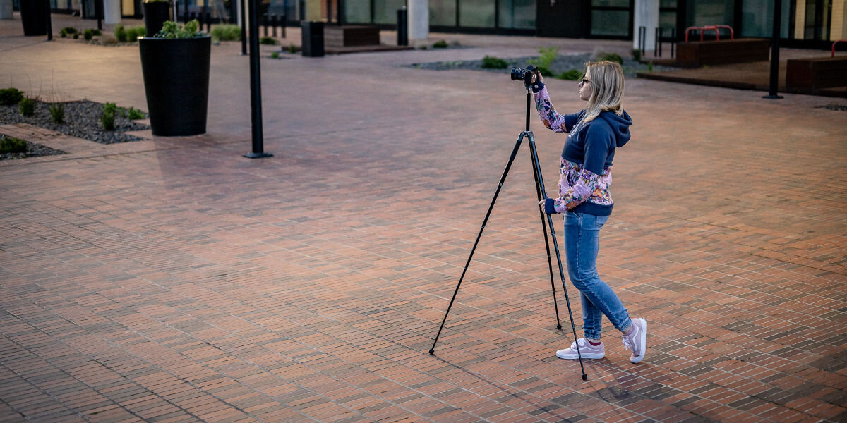 Statyw FOTOPRO Fly-1 Szary, reagowanie, zaprojektowany, odblokowanie, wysokość, osoba obsługuje na ulicy statyw z zamontowany na nim aparatem