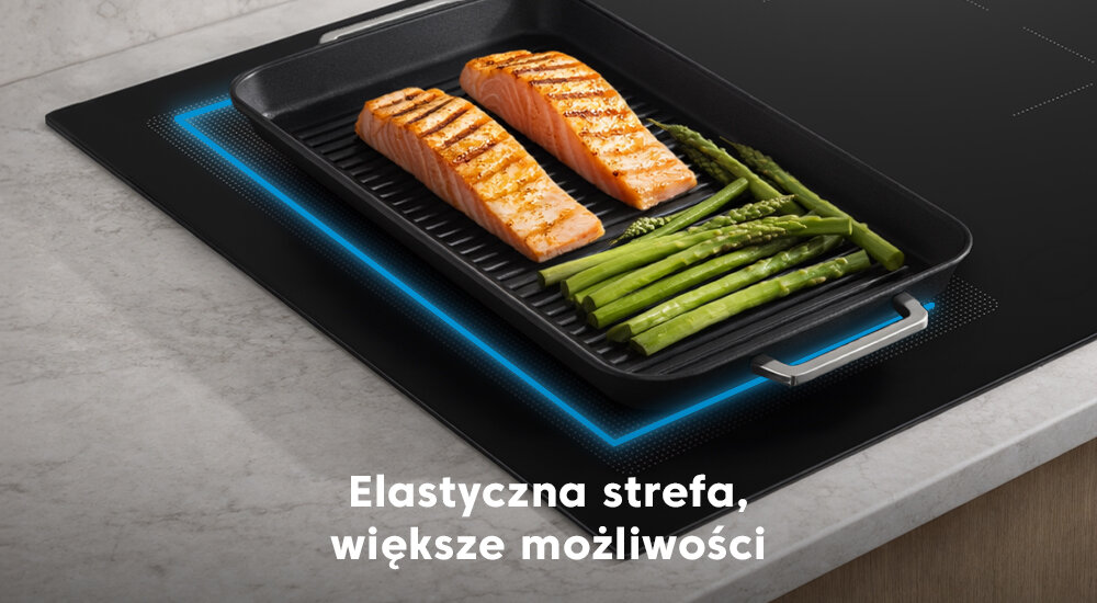 PŁYTA BEKO HII64720SUF2T BPRO 500 Zdjęcie pokazuje dużą patelnię grillową z łososiem i szparagami, ustawioną na połączonej strefie grzewczej płyty indukcyjnej. Podświetlona na niebiesko strefa wskazuje działanie elastycznego pola IndyFlex