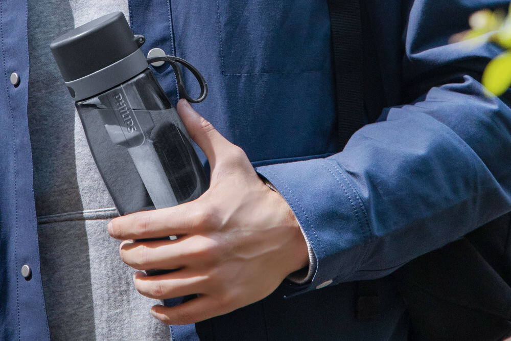 Butelka filtrująca PHILIPS GoZero AWP2731GRR/58 Mężczyzna trzymający w dłoni ciemną butelkę Philips z widocznym wewnątrz wkładem filtrującym.