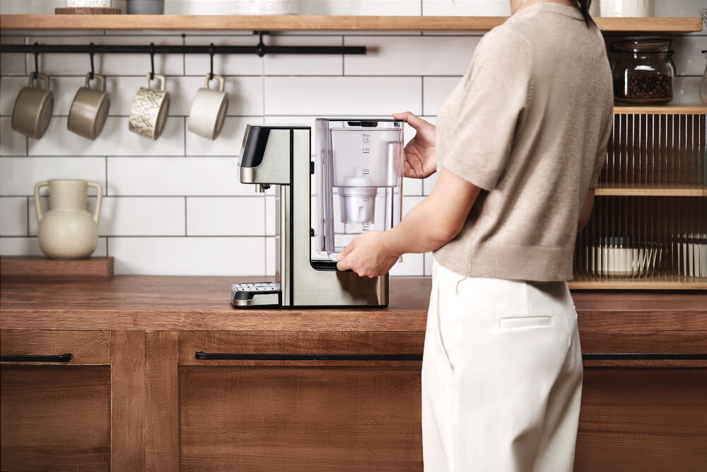 Dyspenser do wody PHILIPS ADD5910M/10 Kobieta montuje przezroczysty zbiornik na wodę z filtrem w tylnej części urządzenia dystrybutor wody Philips. Stabilna konstrukcja i łatwa obsługa na kuchennym blacie.