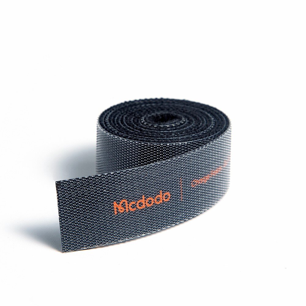 Czarna taśma rzepowa zwinięta w rolkę z widocznym pomarańczowym napisem \'Mcdodo\'.