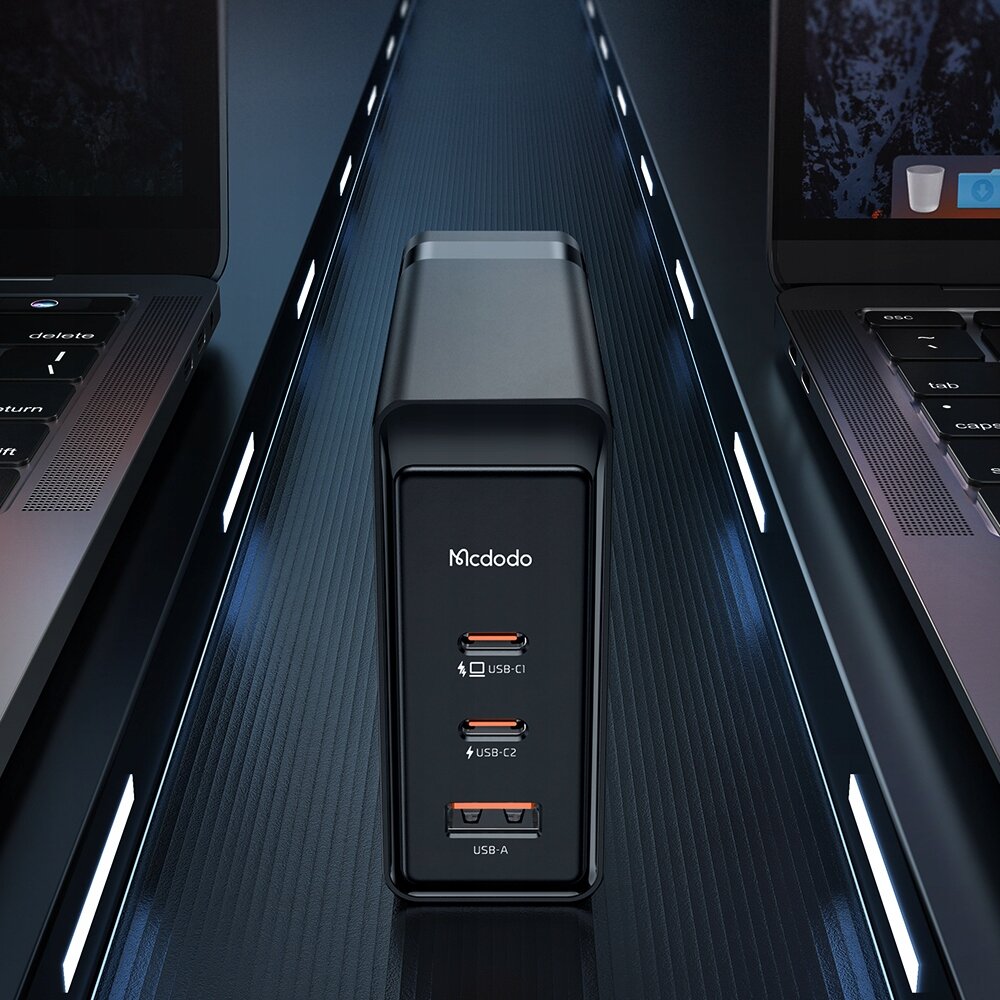 Na obrazie widoczna jest czarna ładowarka z trzema portami: dwoma USB-C oznaczonymi jako USB-C1 i USB-C2 oraz jednym USB-A. Na ładowarce znajduje się logo \'Mcdodo\'.