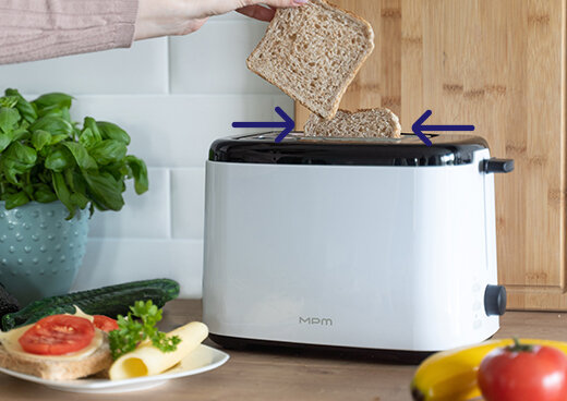 Zbliżenie na kromkę chleba wkładaną do tostera  MTO-07. Tle druga kromka chleba otoczona strzałkami.