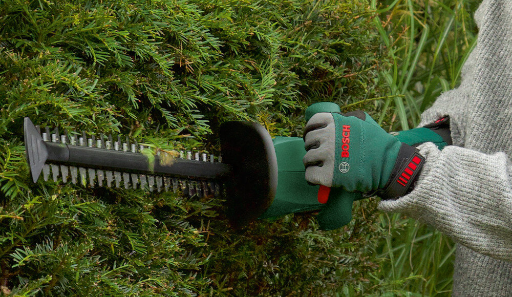 Nożyce do żywopłotu BOSCH Easy HedgeCut 18V-52-13 ogród osoba tnie żywopłoty trzymając nożyce w dłoniach lekka i ergonomicznie zaprojektowana konstrukcja miękka powłoka antypoślizgowa komfortowy włącznik ułatwia precyzyjne prowadzenie narzędzia zmniejsza zmęczenie dłoni stabilny chwyt