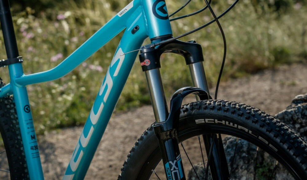 Rower górski MTB KELLYS Vanity 10 M14 26 cali męski Zielony rower typu hardtail przedni amortyzator marki SR Suntour ułatwia najeżdżanie na przeszkody niweluje wstrząsy na kierownicy niska masa roweru duża sztywność