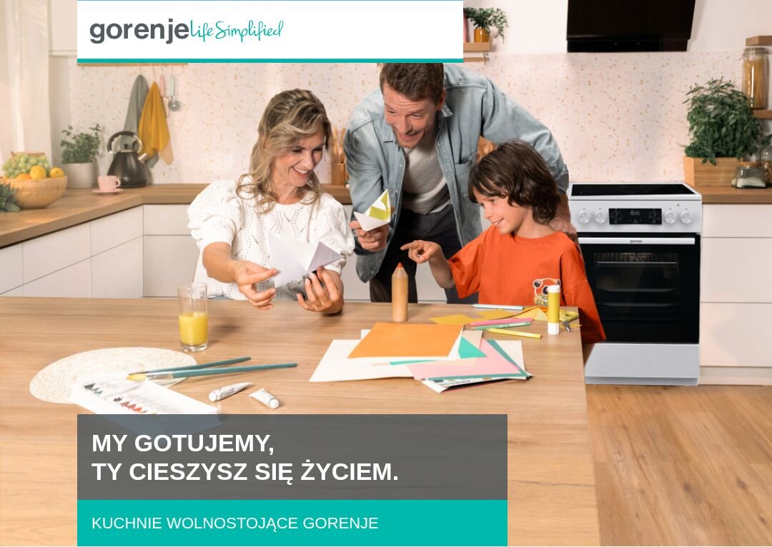 KUCHNIA GORENJE GECS6C70WC Rodzina złożona z dwóch dorosłych i dziecka spędza czas przy kuchennym stole, wycinając kolorowe elementy z papieru, w tle widoczna jest zabudowa kuchenna z kuchnią wolnostojącą Gorenje, a u dołu znajduje się napis „MY GOTUJEMY, TY CIESZYSZ SIĘ ŻYCIEM. KUCHNIE WOLNOSTOJĄCE GORENJE”