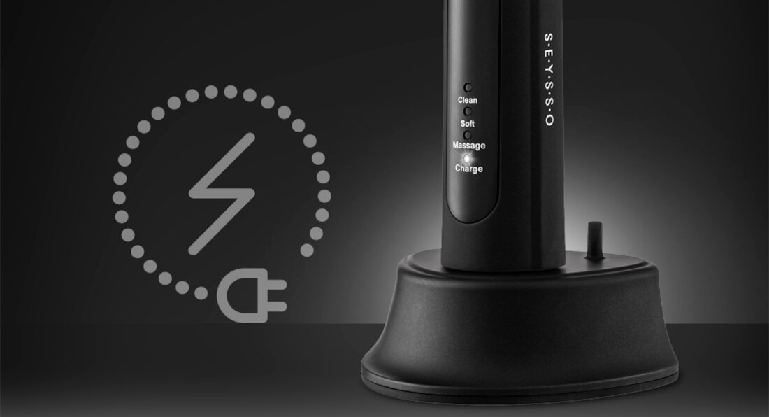 Czarna szczoteczka soniczna na podstawce z widocznymi trybami: Clean, Soft, Massage, Charge. Obok znajduje się symbol ładowania z wtyczką elektryczną.