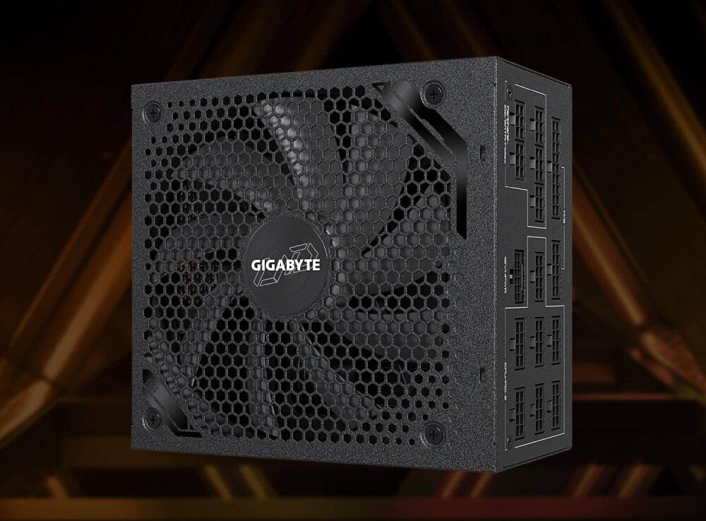 Zasilacz GIGABYTE UD1300GM PG5 Zasilacz z widocznym dużym wentylatorem o konstrukcji siatkowej, z logo producenta pośrodku, sfotografowany pod kątem z widocznymi portami modularnymi z boku, japońskie kondensatory, certyfikaty