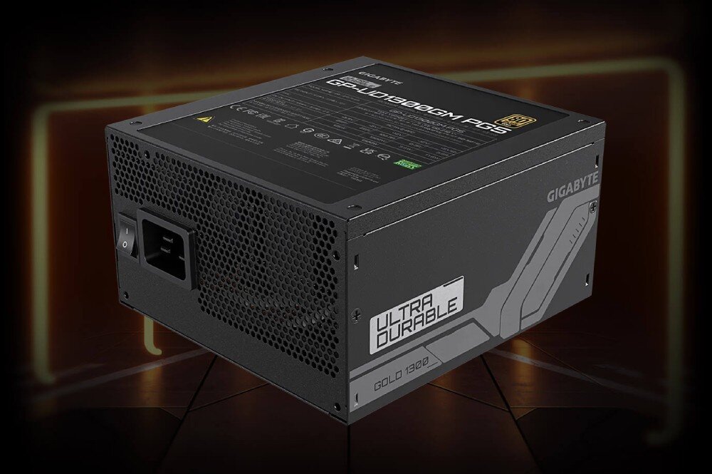 Zasilacz GIGABYTE UD1300GM PG5 Widok tylnej części urządzenia z gniazdem zasilania, włącznikiem i etykietą informacyjną, na której widnieje napis 'Ultra Durable Gold 1300', tło utrzymane w ciemnych, pomarańczowych tonach, sprawność