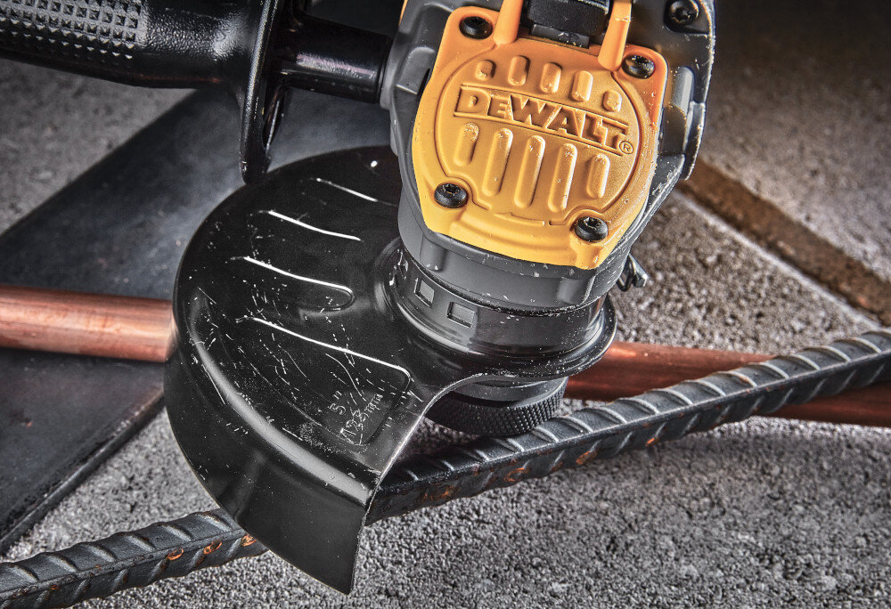 Szlifierka kątowa DEWALT DCG409H2T szlifierka leży na metalowych rurkach zbliżenie na osłonę zabezpieczone siatką otwory wlotowe powietrza długa żywotność silnika zmniejsza potrzebę serwisowania lekka waga 1,8 kg niewielka konstrukcja