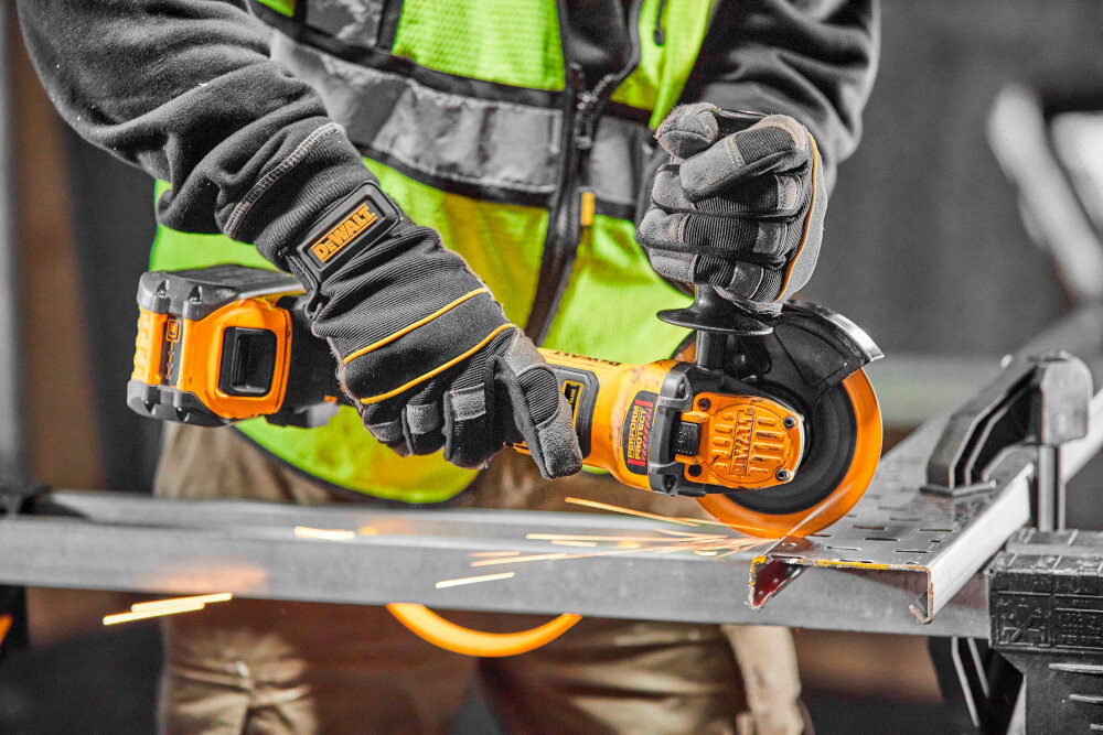 Szlifierka kątowa DEWALT DCG409H2T osoba używa szlifierki tnie metalowy element beznarzędziowo ustawiana osłona tarczy ułatwia to pracę w zmiennych warunkach bezpieczeństwo sprawnie reagować na bieżące potrzeby przycisk blokady wrzeciona M14 szybka zmiana tarczy nie wymaga zastosowania narzędzi współpracuje z tarczą o średnicy 125 mm