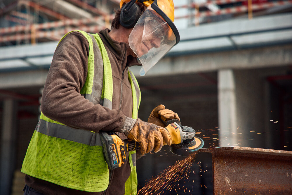 Szlifierka kątowa DEWALT DCG405H2T-QW osoba używa szlifierki szlifuje metalowy element kontrola w każdej sytuacji wszechstronność zastosowań mobilność zasilane akumulatorowe