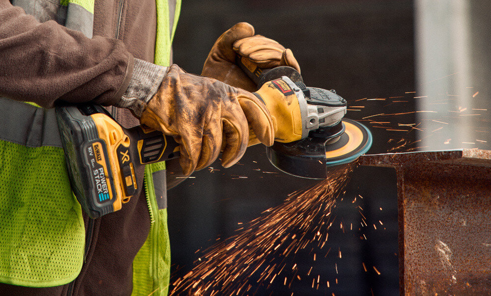 Szlifierka kątowa DEWALT DCG405H2T-QW osoba używa szlifierki szlifuje metalowy element elektroniczny hamulec ogranicza ryzyko przypadkowych urazów wbudowane sprzęgło elektroniczne
