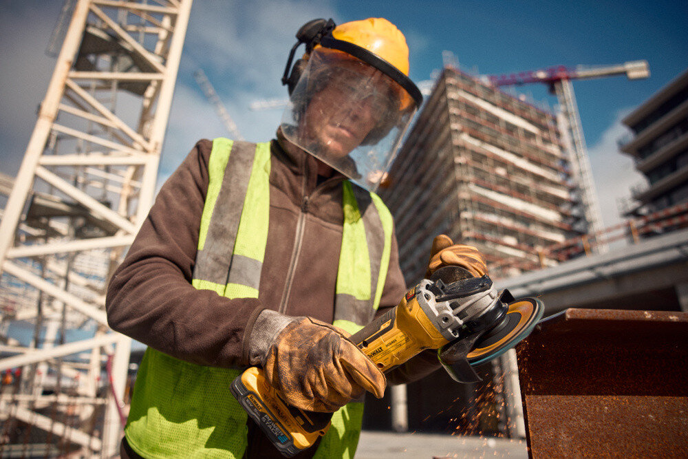 Szlifierka kątowa DEWALT DCG405H2T-QW osoba używa szlifierki szlifuje metalowy element suwakowy włącznik z blokadą antypoślizgowa dwukomponentowa obudowa stabilny chwyt dwupozycyjne mocowanie uchwytu bocznego indywidualne dopasowanie do stylu pracy i dominującej ręki