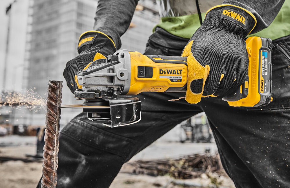 Szlifierka kątowa DEWALT DCG405H2T-QW osoba używa szlifierki tnąc metalową rurkę zabezpieczone siatką otwory wlotowe powietrza długa żywotność silnika zmniejsza potrzebę serwisowania lekka waga 1,75 kg niewielka konstrukcja
