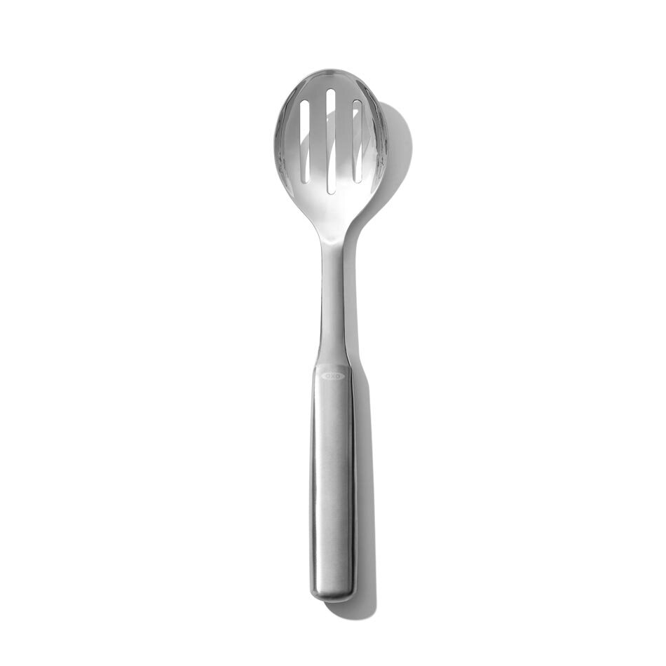 Na obrazie widoczna jest metalowa łyżka do serwowania z trzema otworami w części nabierającej. Na uchwycie znajduje się logo \'OXO\'.