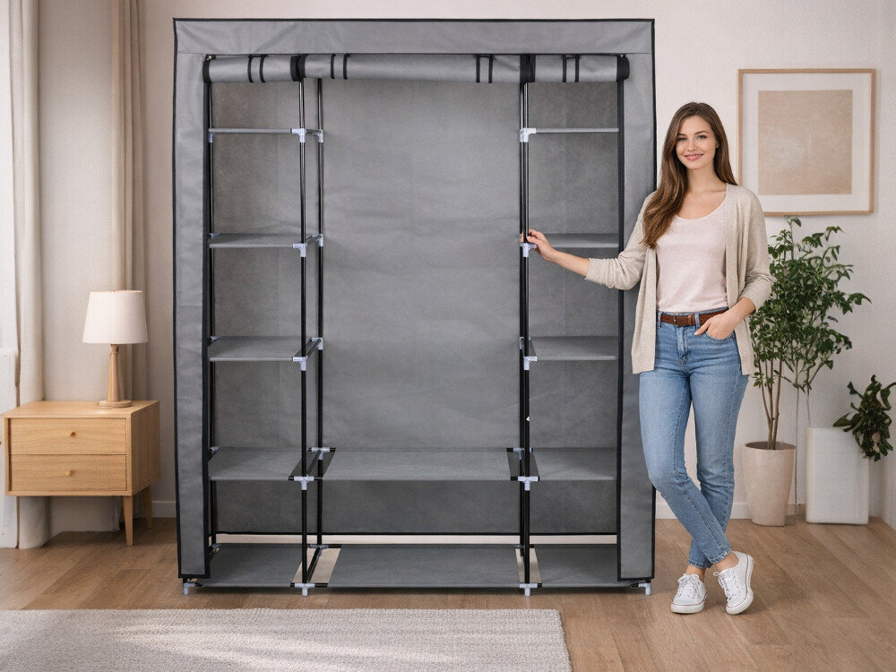 Na zdjęciu znajduje się ciemnoszara szafa tekstylna z kilkoma półkami, ustawiona w jasnym wnętrzu. Obok szafy stoi osoba ubrana w jasne ubrania, uśmiechająca się.