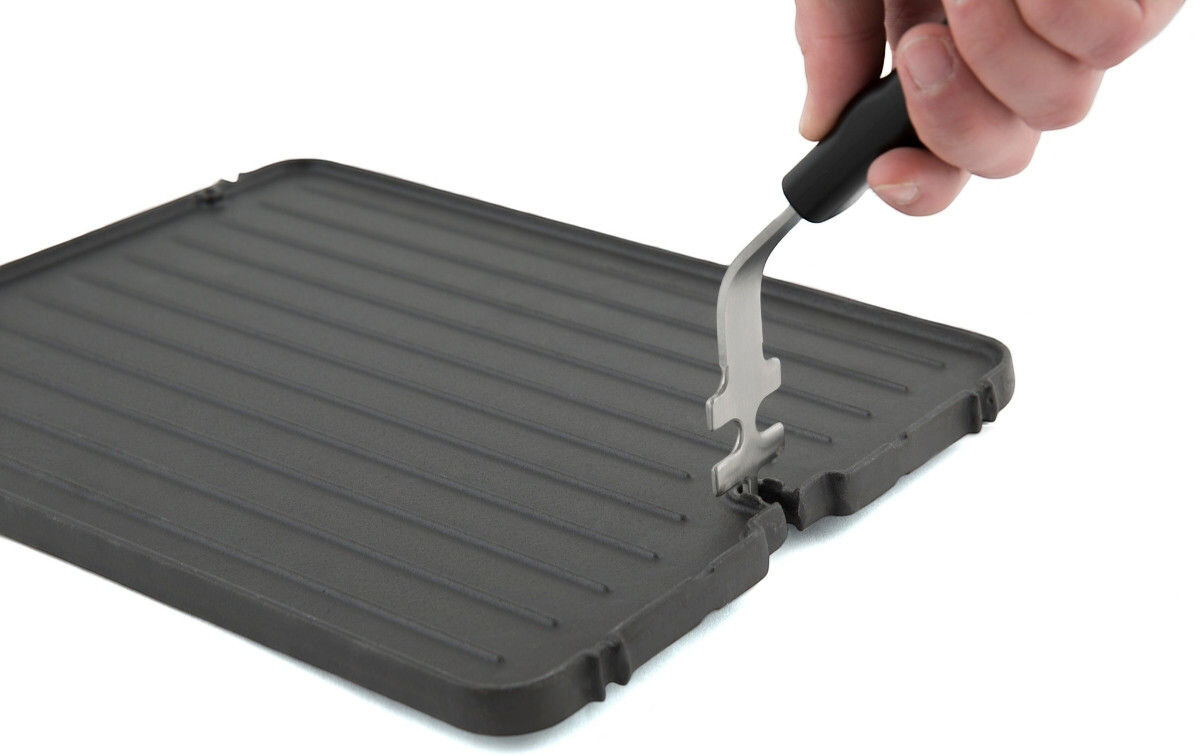 Płyta do grilla żeliwna BROIL KING GEM PORTA-CHEF 11237 33.5 x 26.5 cm, uchwyt, przenoszenie płyty, bezpieczeństwo, wygoda, Zbliżenie na rękę unoszącą żeliwną płytę grillową specjalnym stalowym uchwytem.