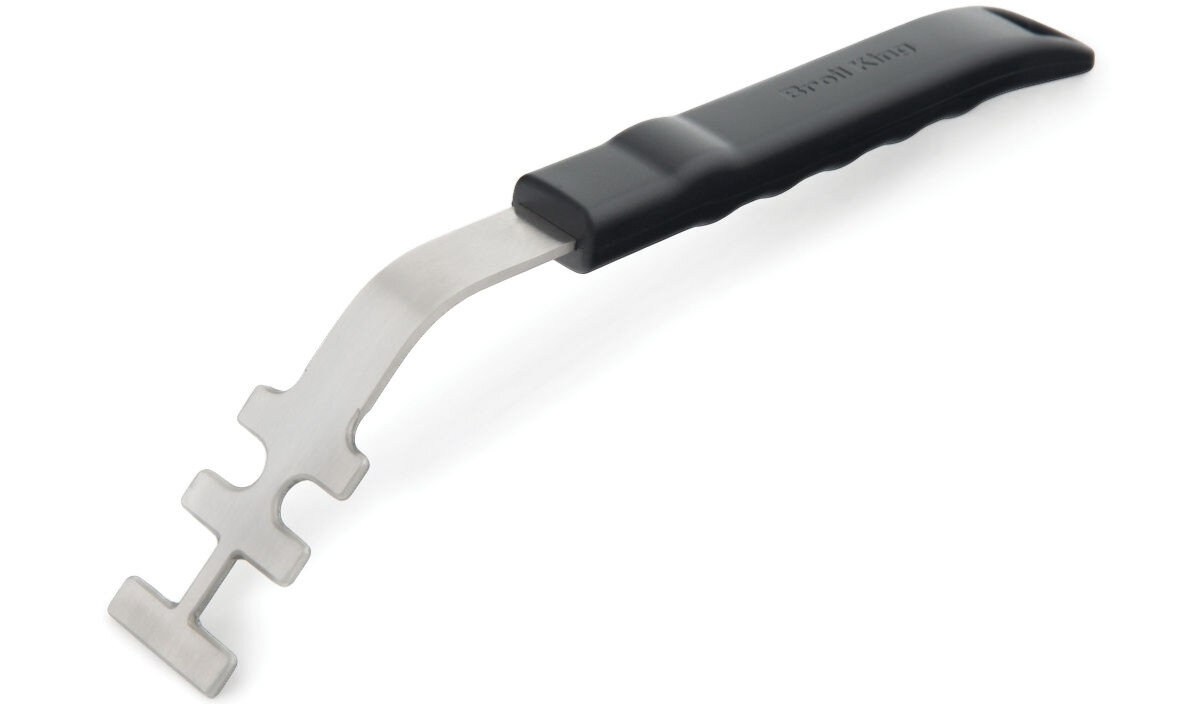 Metalowy uchwyt wielofunkcyjny z czarną plastikową rączką, posiadający kilka ząbków na końcu. Na rączce widoczny jest napis \'Broil King\'.