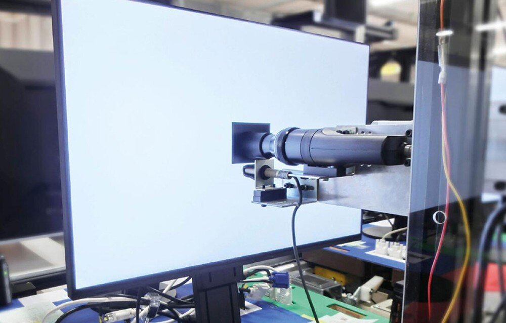 Monitor EIZO ColorEdge CS2400R Proces kalibracji monitora w warunkach laboratoryjnych. Przed ekranem ustawione jest urządzenie pomiarowe skierowane w stronę świecącego monitora, kalibracja, jednolitość