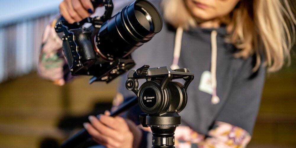 Kobieta montuje aparat na statywie Fotopro S5i Pro. W jednej ręce trzyma aparat, drugą chwyta za głowicę.