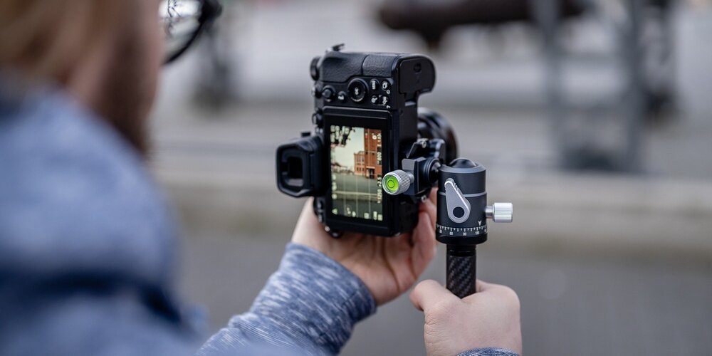 Zbliżenie na aparat zamocowany na statywie Fotopro X-Aircross 3, z widoczną poziomicą i regulacją głowicy kulowej.