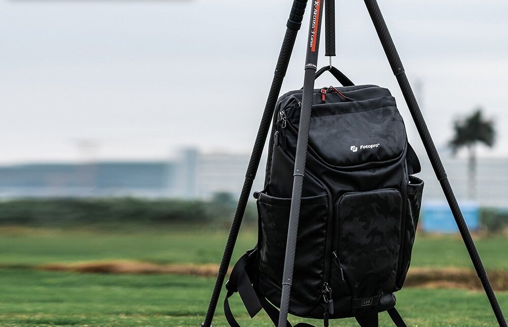 Statyw Fotopro X-Aircross 3 z aparatem, obciążony plecakiem dla zwiększenia stabilności podczas fotografowania w plenerze.