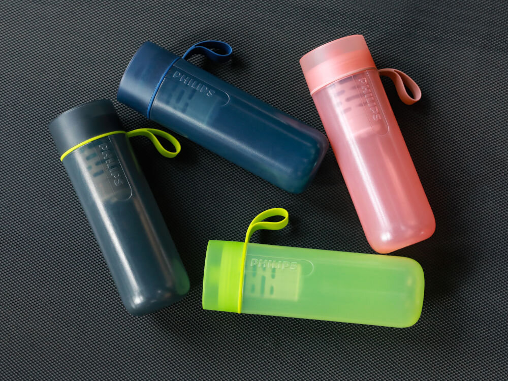 Butelka filtrujaca PHILIPS GoZero AWP2712BLR/58 Czarny Cztery kolorowe butelki sportowe Philips GoZero Active leżące na czarnej macie treningowej, prezentujące ich matowe wykończenie i elastyczne uchwyty.