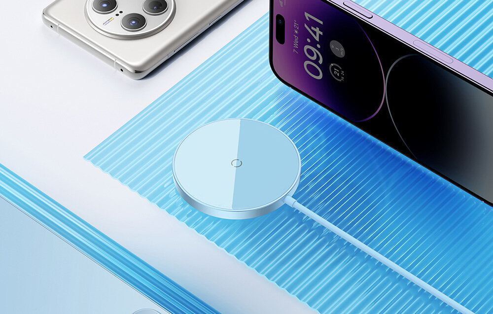 Na obrazie widoczna jest niebieska magnetyczna ładowarka indukcyjna z okrągłą powierzchnią, podłączona kablem. Obok znajdują się dwa smartfony na niebieskim tle.