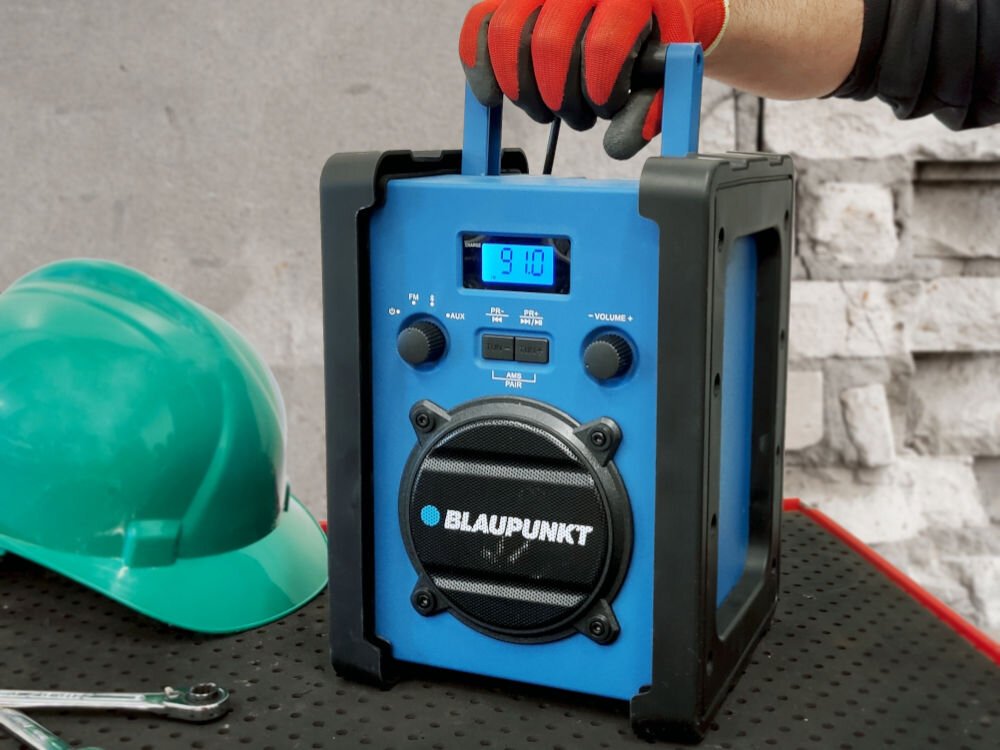Radio budowlane BLAUPUNKT PP30BT JOBSITE, radio, stacje, strojenie, pamięć, antena, Radio stoi trzymane na blacie wraz z kasiem budowlanym na tle placu budowy