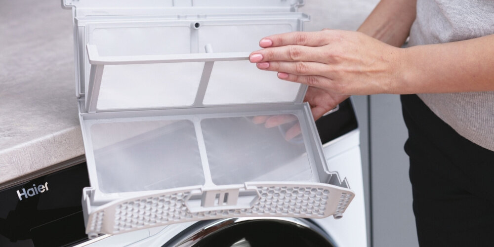 SUSZARKA HAIER I-PRO 3 HD90-A3939-S zdjęcie lifestyle filtr dłoń panel logo Czystość ubrań i urządzenia filtr 3 w 1 wyłapuje wszystkie zanieczyszczenia proste szybkie usuwanie włókien sierści
