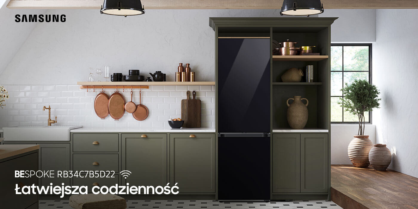 Lodówka Samsung Bespoke RB34C7B5D22 z fabrycznie zainstalowanymi panelami drzwiowymi w kolorze głębokiej czerni. Urządzenie jest dostępne w ofercie sklepu Media Expert Kuchnia z lodówką o czarnym szklanym froncie, otoczona zielonymi szafkami i półkami z drewnianymi akcesoriami. Na obrazie widoczny jest tekst: \'SAMSUNG BESPOKE RB34C7B5D22 Łatwiejsza codzienność\'.