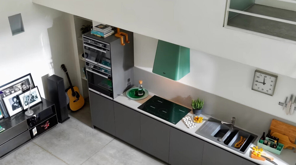 Piekarnik FRANKE FSM 45 MW XS Widok z boku pokazuje piekarnik z uchylonymi drzwiczkami w stylowej kuchni. W tle widoczne jest duże okno doświetlające pomieszczenie