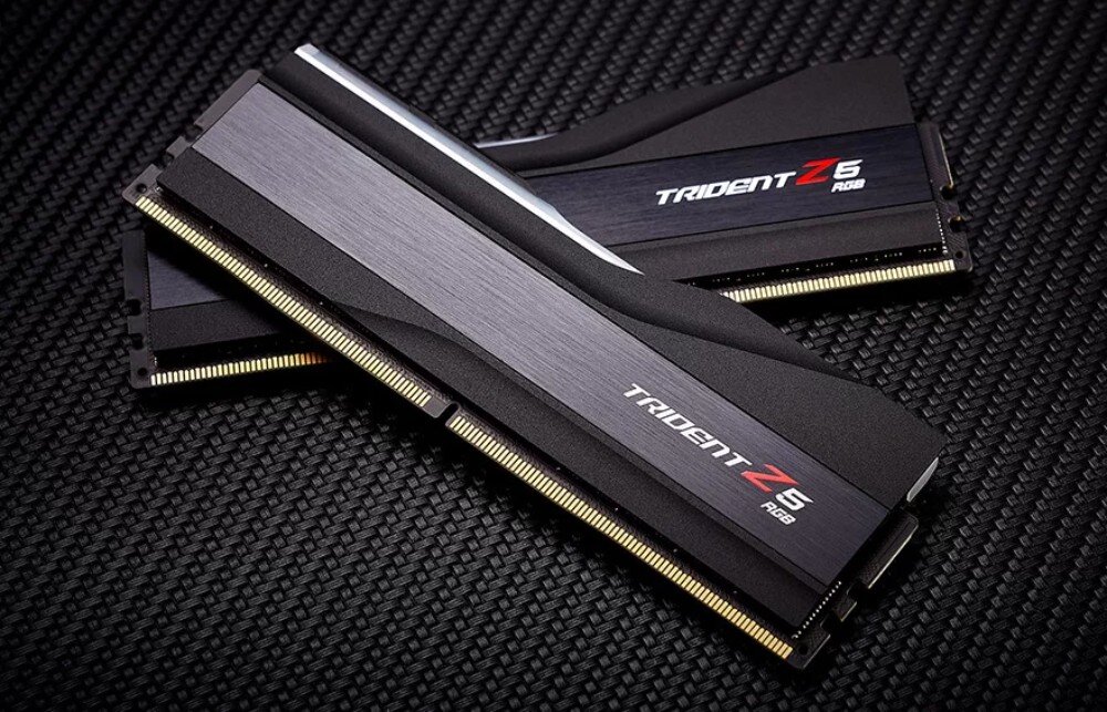 Pamięć RAM G.SKILL Trident Z5 RGB Dwa moduły pamięci RAM ułożone na ukos jeden na drugim na wzorzystym tle Widoczne stykowe złącza oraz aluminiowy radiator z napisem
