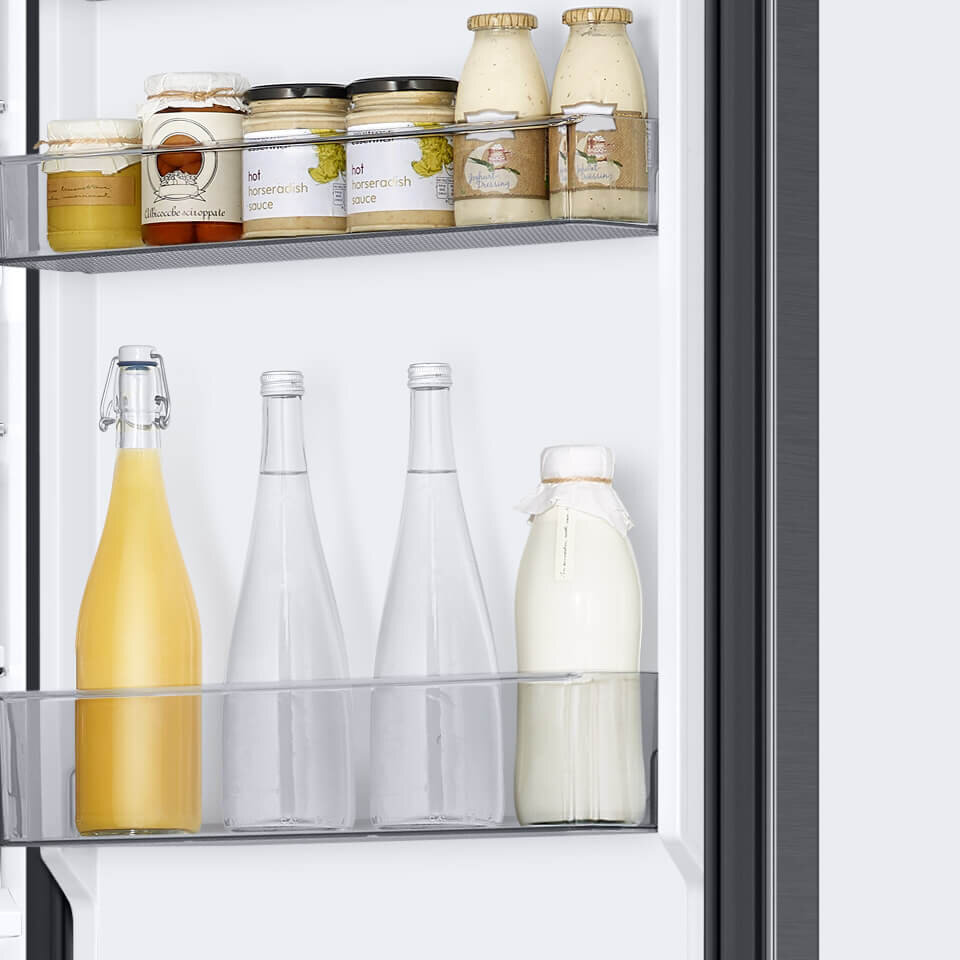 Wnętrze lodówki z widocznymi półkami na drzwiach, na których znajdują się słoiki z sosami i butelki z napojami. Na słoikach widoczny jest tekst: \'hot horseradish sauce\'.