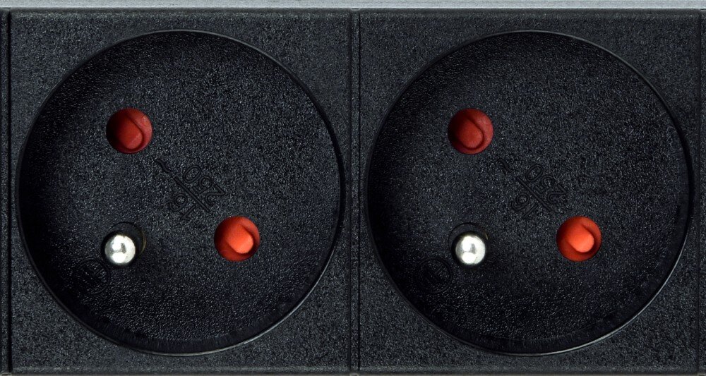 Listwa ENERGENIE EG-PDU-9F2F Zbliżenie na dwa czarne gniazda zasilające z bolcem uziemiającym, czerwonymi zabezpieczeniami otworów oraz wytłoczonym napisem '16 / 250 ~'