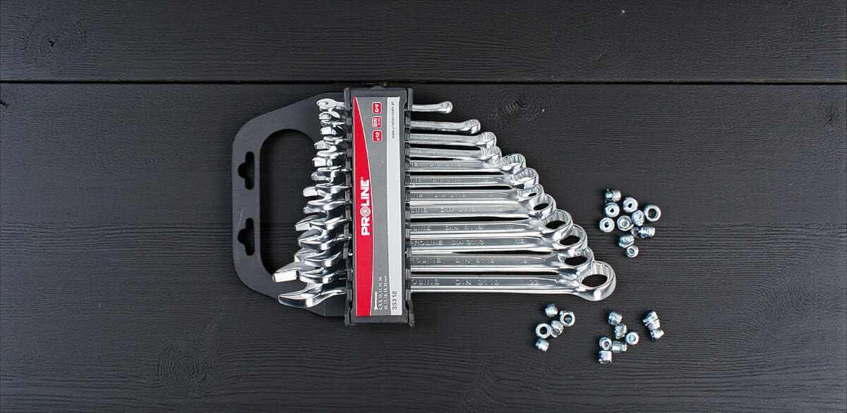 Zestaw kluczy płasko-oczkowych PROLINE 35312 6-22 mm (12 sztuk), rozmiary, pokrywanie, uniwersalne, Wszechstronność, na czarnym drewnie leży zestaw kluczy