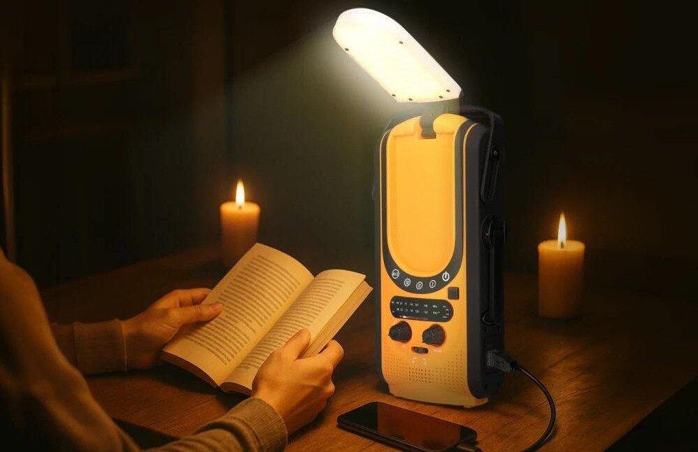 Radio EXTRALINK EPS-6000 funkcje awaryjne przenośne zasilanie wielotrybowe, radio stojące na stole, osoba czytająca książkę