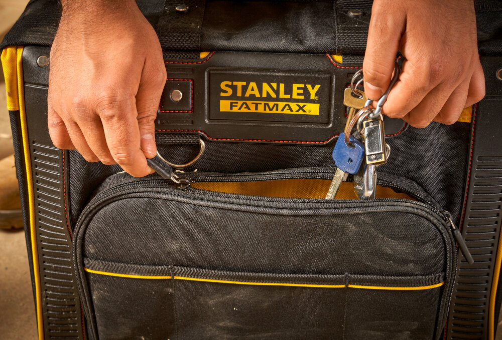 Torba narzędziowa STANLEY FMST1-80148 podłoga zbliżenie na jedną z kieszeni osoba chowa do wnętrza klucze szerokie otwarcie wygodny dostęp do całego wnętrza ogranicza czas przygotowania do pracy wymiary 500 × 455 × 330 mm dobrze dobrane proporcje