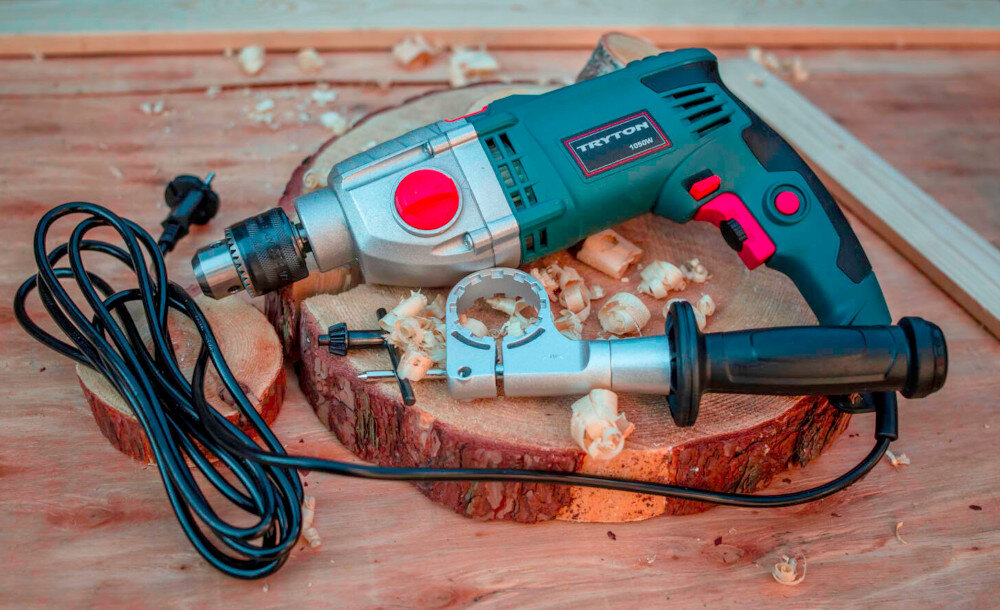 Wiertarka udarowa TRYTON TDW1050A pomieszczenie drewniany blat roboczy na blacie leży wiertarka obok rękojeść dodatkowa precyzyjna praca wszechstronne zastosowanie dokładność