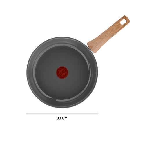 Na obrazie widoczna jest patelnia z szarym wnętrzem i drewnianą rączką. Na środku patelni znajduje się czerwony okrągły symbol.