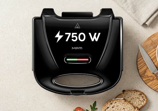 Ujęcie z góry: Opiekacz do kanapek MOP-47 na blacie, dwie diody świecą się na zielono i czerwono. Ikona błyskawicy i 750 W.