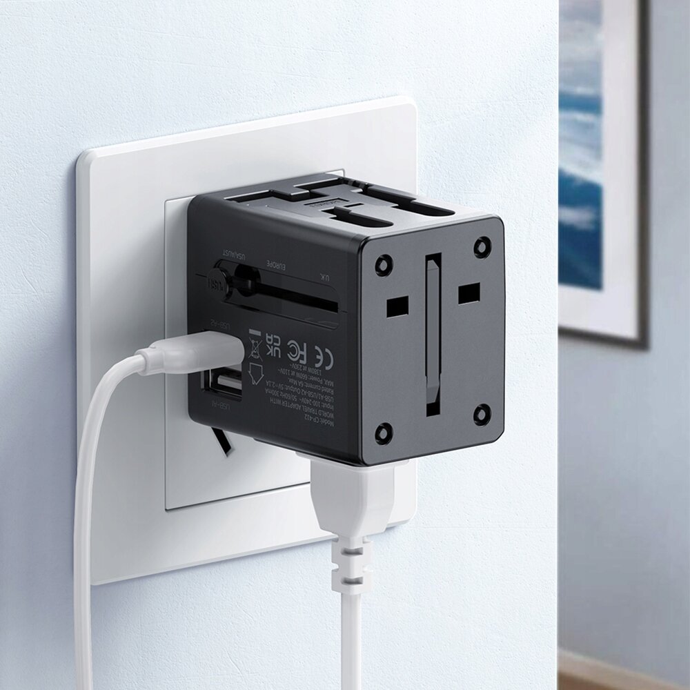 Na zdjęciu widać czarną ładowarkę USB z adapterem podłączoną do gniazdka elektrycznego. Ładowarka ma kilka portów i jest podłączona do niej biały kabel.