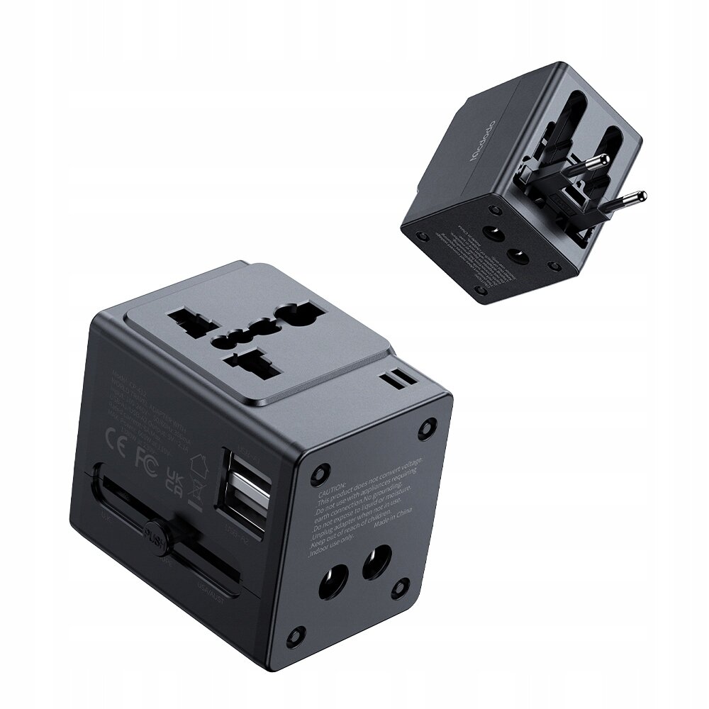 Na obrazie widoczna jest czarna ładowarka USB z adapterem, posiadająca różne typy wtyczek. Na urządzeniu znajdują się oznaczenia CE, FCC oraz dwa porty USB.