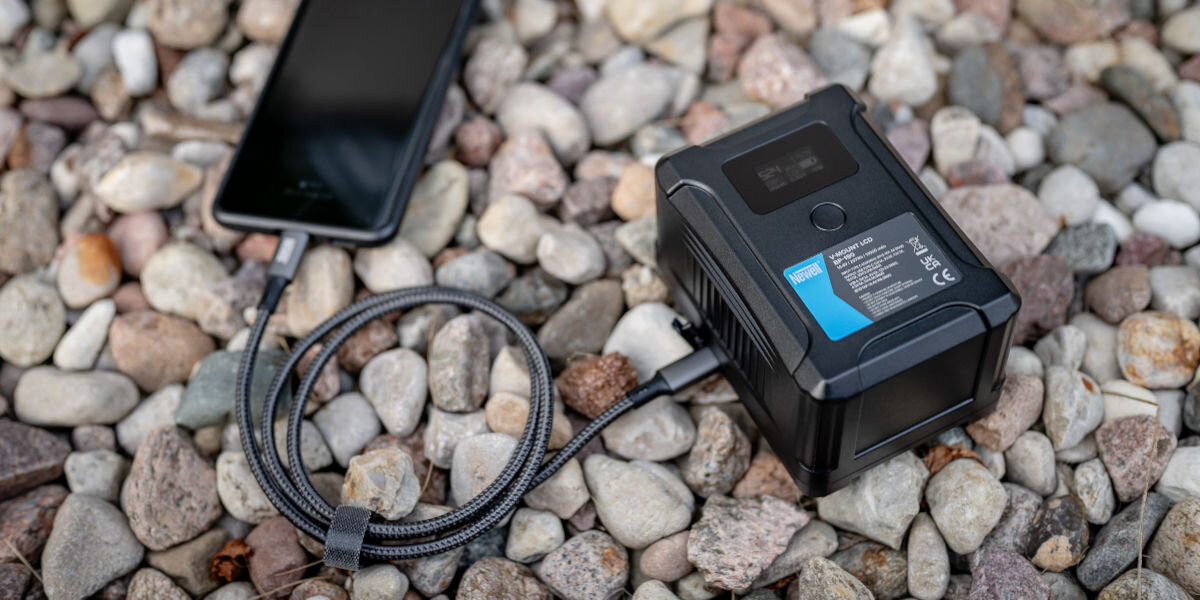 Akumulator NEWELL 14000 mAh do BP-190 LCD V-Mount, porty, usb, pojemy, powerbank, na kamiennym podłożu leży akumulator zasilający smartfona